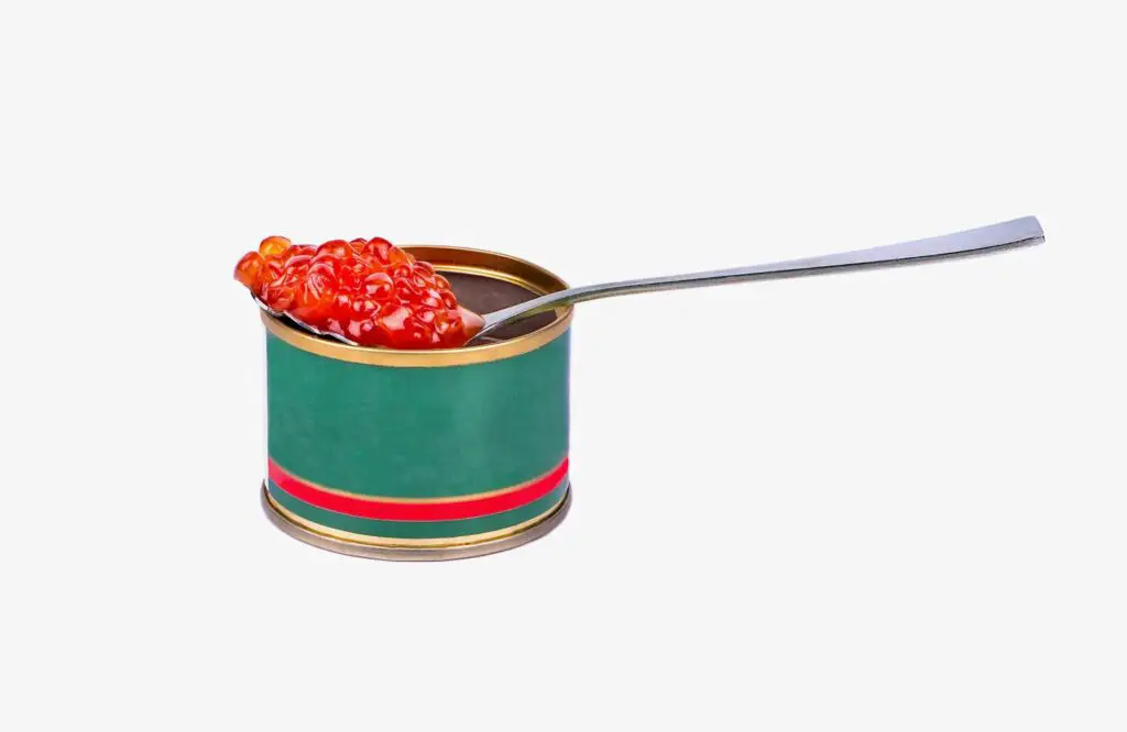 A tin and a spoon full of caviar on it